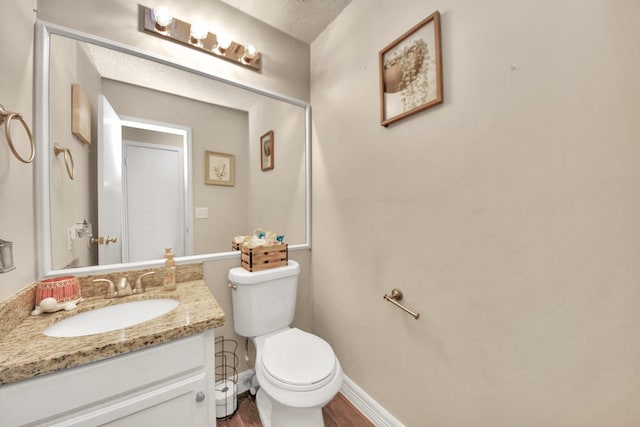 bathroom featuring hardwood / wood-style flooring, vanity, toilet, and a textured ceiling