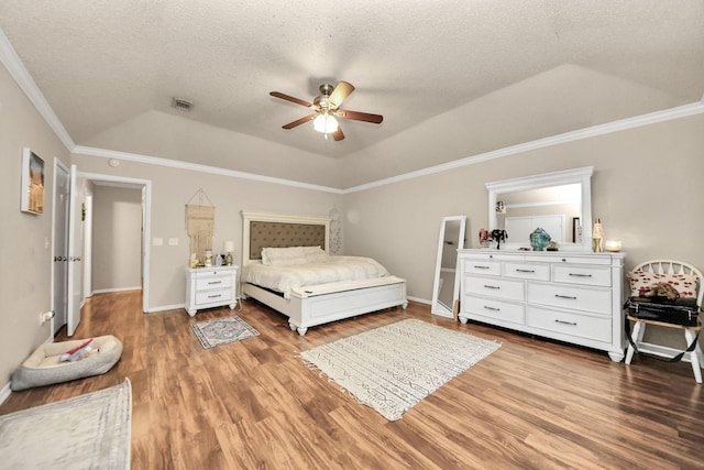 bedroom with hardwood / wood-style flooring, ceiling fan, ornamental molding, a textured ceiling, and a raised ceiling