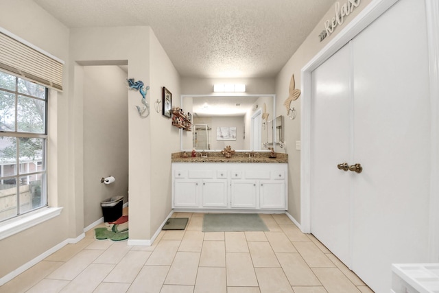 bathroom featuring tile patterned floors, vanity, a textured ceiling, and a wealth of natural light