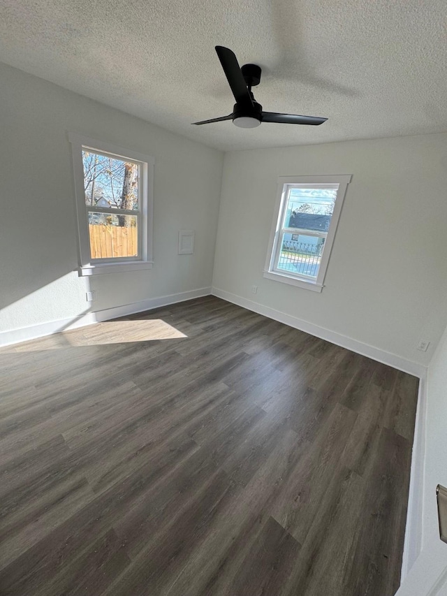 empty room featuring a healthy amount of sunlight, dark hardwood / wood-style flooring, and a textured ceiling