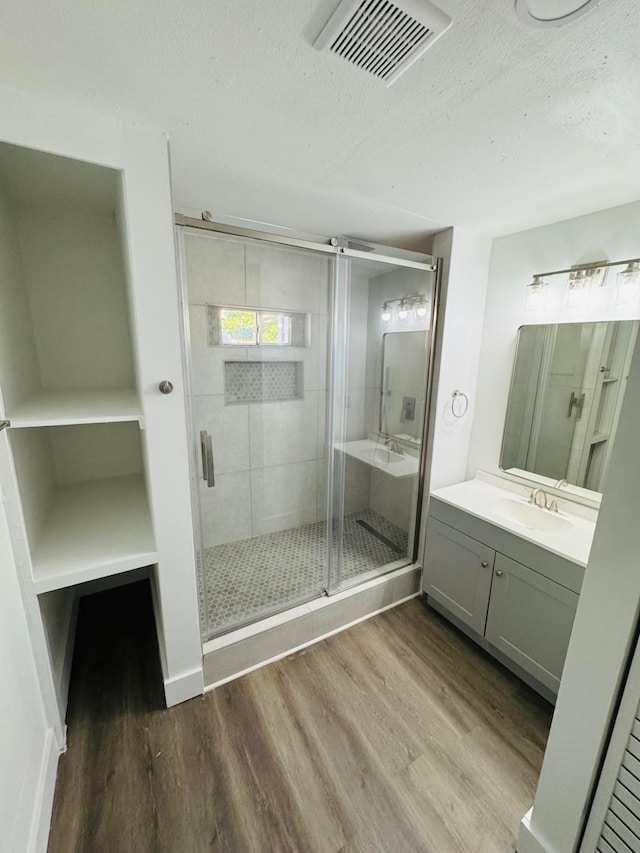 bathroom with vanity, a shower with door, hardwood / wood-style floors, and a textured ceiling