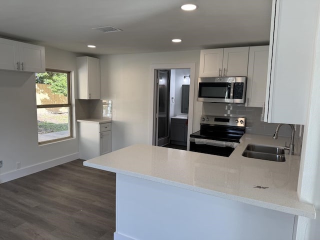 kitchen with sink, stainless steel appliances, kitchen peninsula, and white cabinets