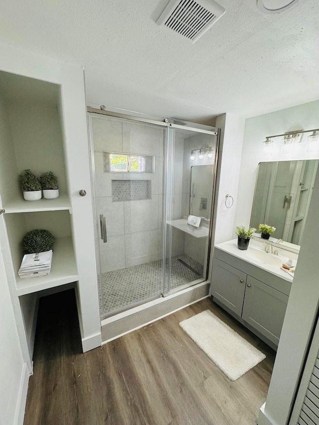 bathroom featuring vanity, hardwood / wood-style floors, a textured ceiling, and walk in shower