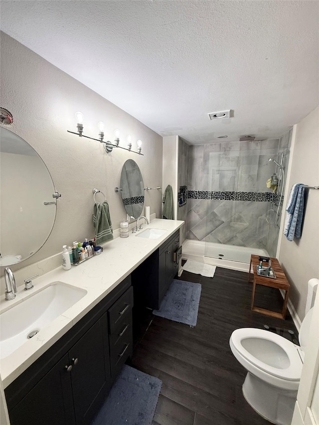 bathroom with vanity, hardwood / wood-style floors, a textured ceiling, and tiled shower