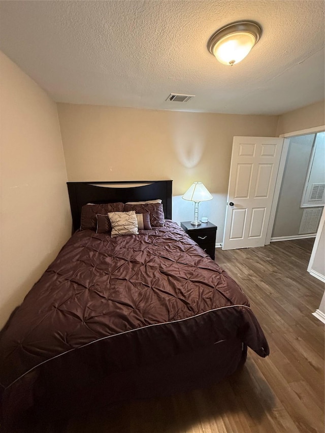 bedroom featuring hardwood / wood-style flooring and a textured ceiling