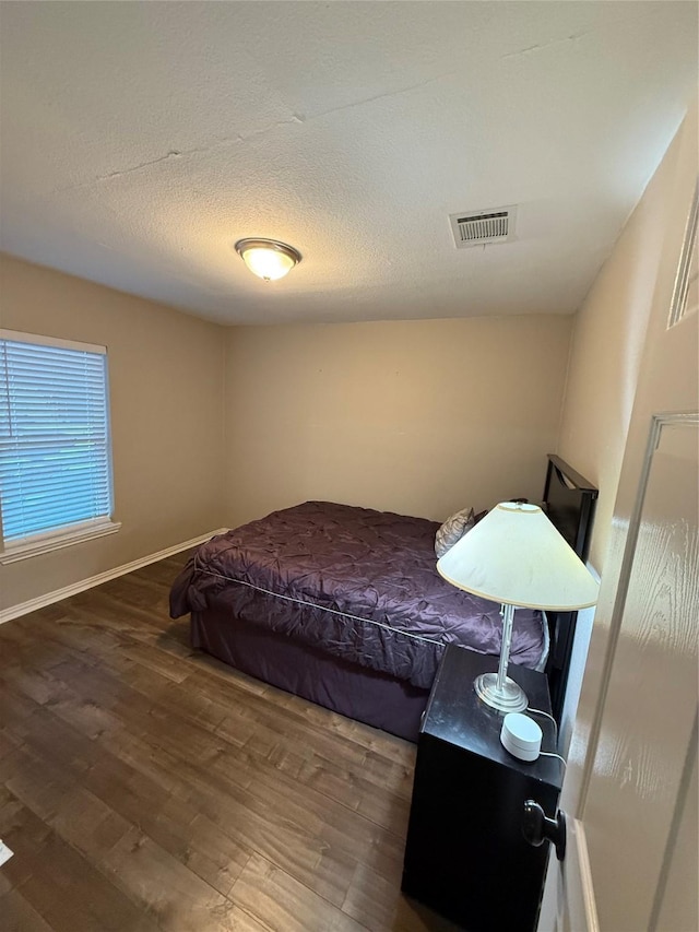 bedroom with dark hardwood / wood-style floors and a textured ceiling