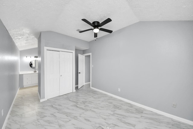 unfurnished bedroom with ceiling fan, lofted ceiling, a textured ceiling, and a closet