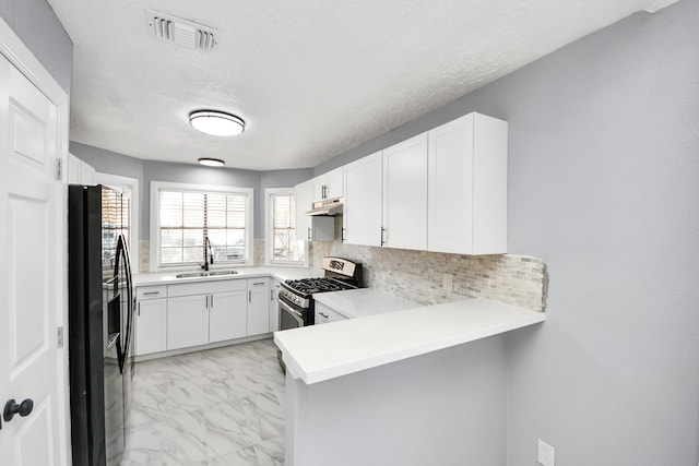 kitchen with white cabinetry, sink, kitchen peninsula, and black fridge