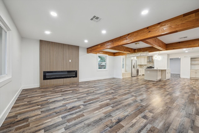 unfurnished living room featuring beam ceiling, dark hardwood / wood-style floors, and a large fireplace