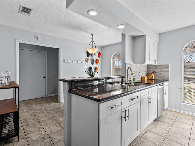 kitchen with white cabinetry, sink, backsplash, stainless steel dishwasher, and kitchen peninsula