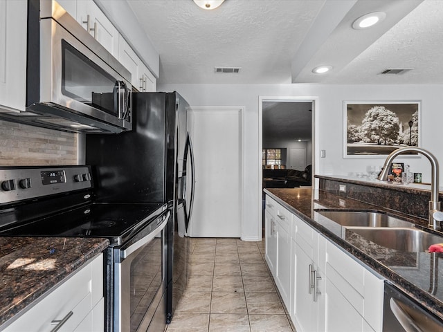 kitchen featuring sink, white cabinets, dark stone counters, stainless steel appliances, and a textured ceiling