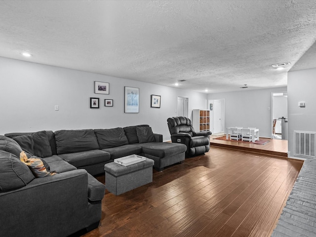 living room featuring dark wood-type flooring and a textured ceiling