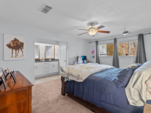 carpeted bedroom with ensuite bathroom, a textured ceiling, and ceiling fan