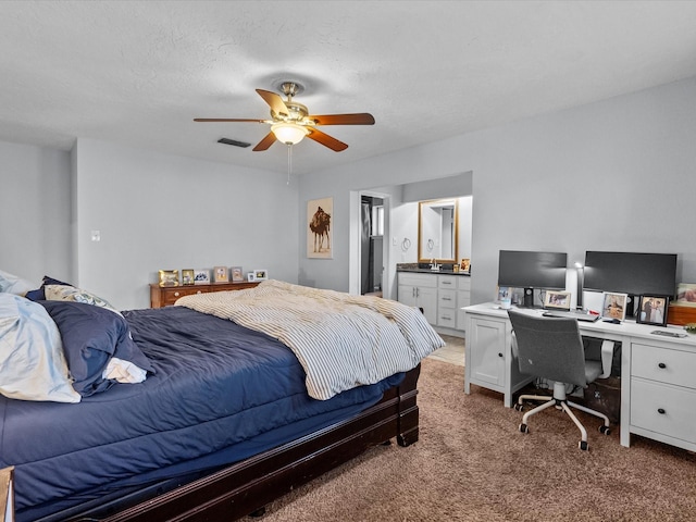 carpeted bedroom featuring ensuite bathroom, a textured ceiling, and ceiling fan