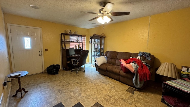 living room featuring ceiling fan and a textured ceiling