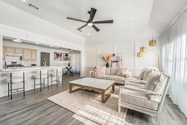 living room featuring lofted ceiling, dark hardwood / wood-style floors, sink, and ceiling fan