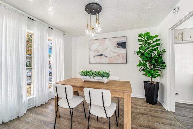 dining space with hardwood / wood-style floors and a textured ceiling