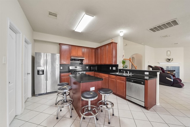 kitchen with light tile patterned flooring, appliances with stainless steel finishes, sink, a kitchen breakfast bar, and a center island