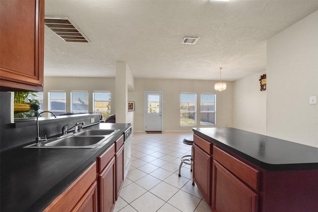 kitchen with a kitchen island, sink, hanging light fixtures, stainless steel dishwasher, and light tile patterned floors