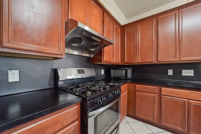 kitchen with light tile patterned floors, range hood, and stainless steel range with gas stovetop