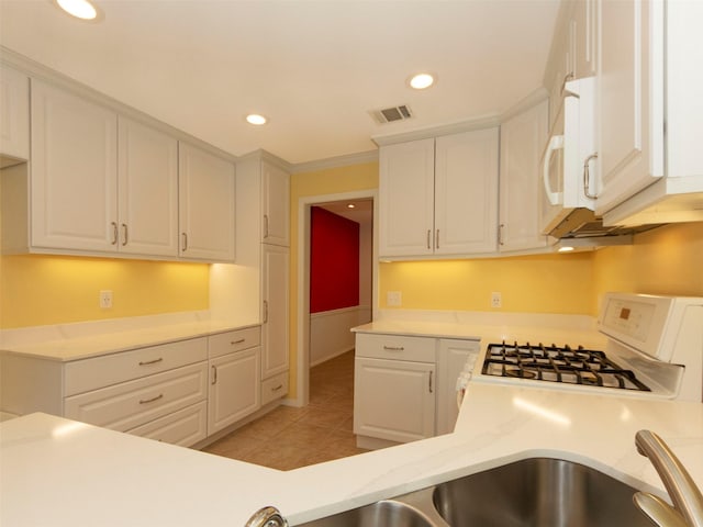 kitchen with white cabinetry, white appliances, ornamental molding, and light tile patterned floors