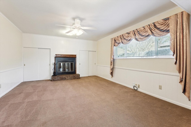 unfurnished living room with ornamental molding, a brick fireplace, carpet floors, and ceiling fan