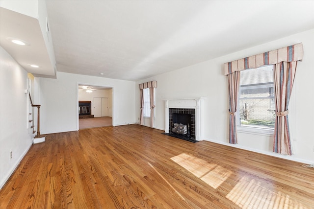 unfurnished living room featuring ceiling fan, a fireplace, and light hardwood / wood-style flooring