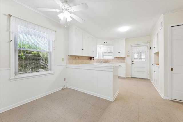 kitchen featuring ceiling fan, backsplash, ornamental molding, white cabinets, and kitchen peninsula