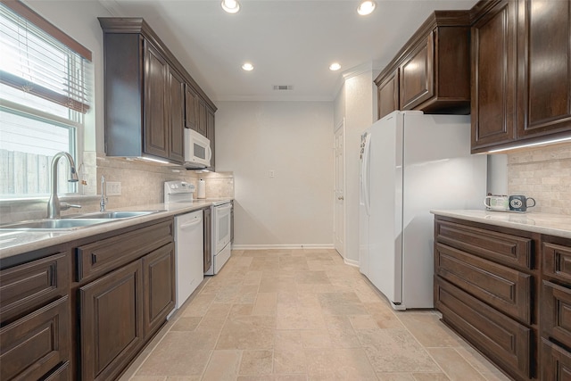 kitchen featuring sink, crown molding, white appliances, backsplash, and dark brown cabinetry