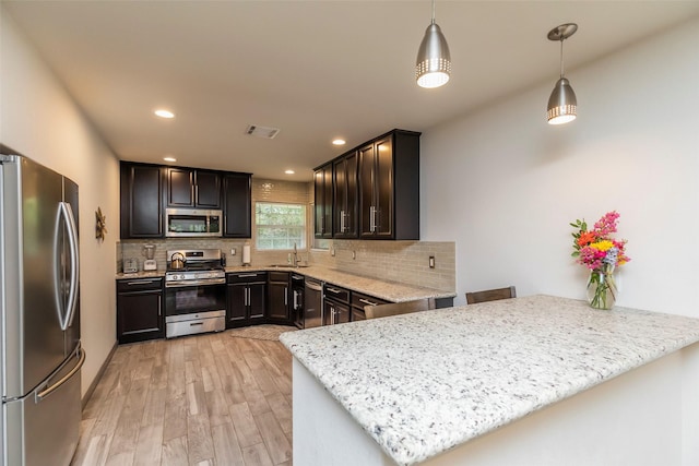 kitchen with pendant lighting, sink, kitchen peninsula, and appliances with stainless steel finishes