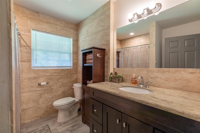 bathroom featuring wood-type flooring, tile walls, vanity, and toilet