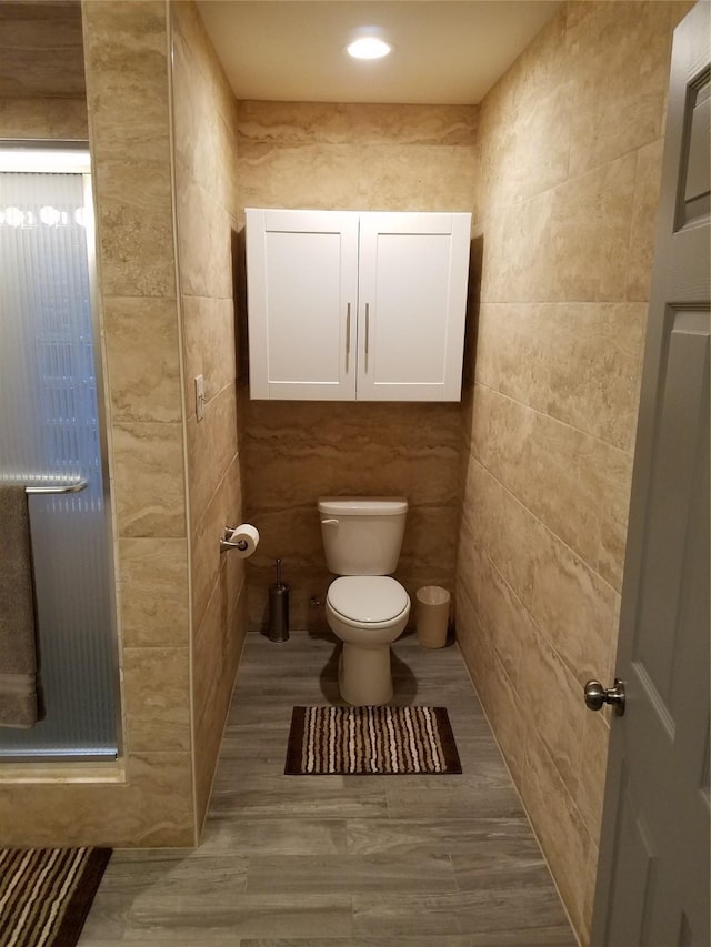 bathroom with a shower with shower door and toilet