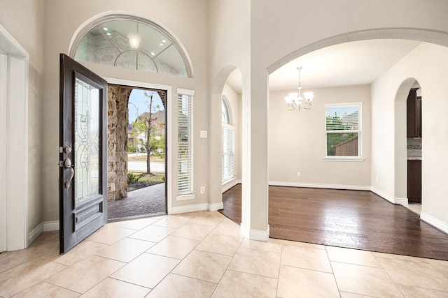 foyer entrance featuring a towering ceiling, a chandelier, and light tile patterned floors