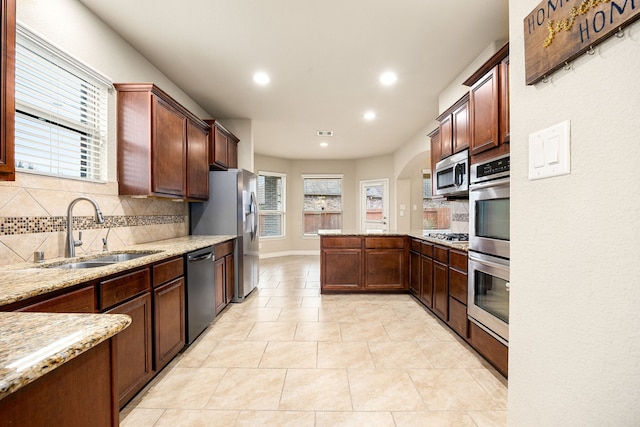 kitchen featuring sink, light tile patterned floors, appliances with stainless steel finishes, light stone countertops, and backsplash