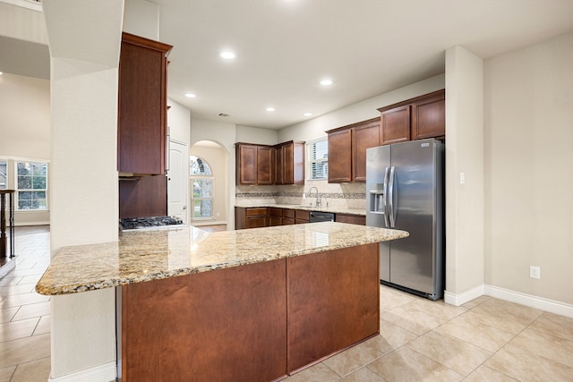 kitchen featuring sink, kitchen peninsula, stainless steel appliances, light stone countertops, and backsplash