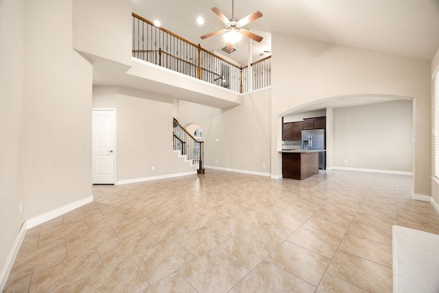 unfurnished living room with ceiling fan and a high ceiling