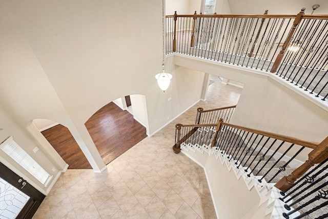 stairway with tile patterned flooring and a towering ceiling