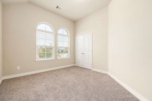 unfurnished room with carpet floors and vaulted ceiling