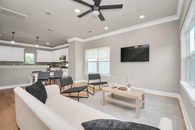 living room featuring crown molding, ceiling fan, and light hardwood / wood-style flooring