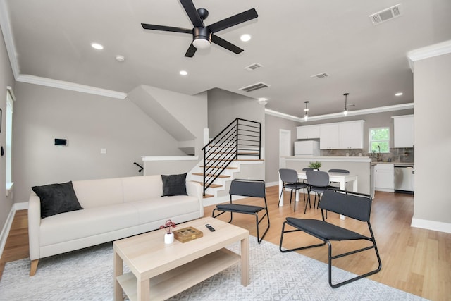 living room with crown molding, ceiling fan, and light hardwood / wood-style floors