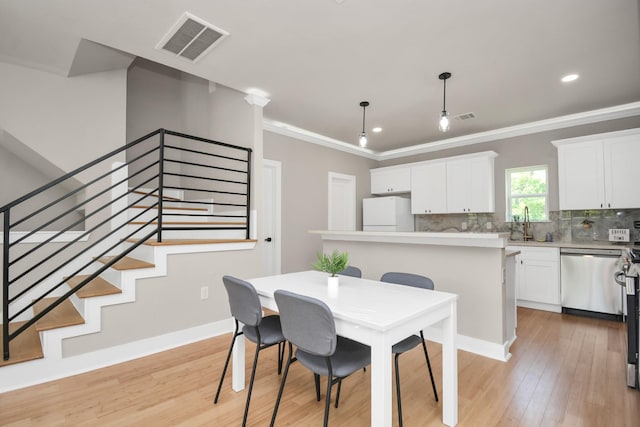 dining space with sink, crown molding, and light hardwood / wood-style floors