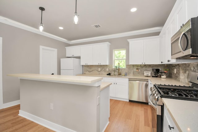 kitchen featuring appliances with stainless steel finishes, decorative light fixtures, white cabinets, decorative backsplash, and a center island