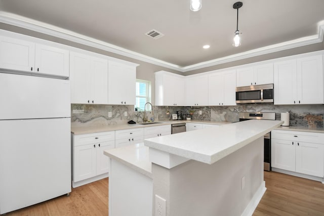 kitchen featuring white cabinetry, stainless steel appliances, a center island, and hanging light fixtures