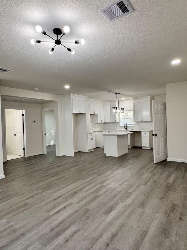 kitchen with white cabinetry, a center island, hanging light fixtures, and hardwood / wood-style flooring