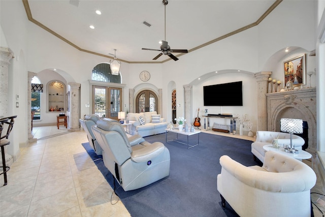 living room with french doors, light tile patterned floors, a towering ceiling, ceiling fan, and decorative columns