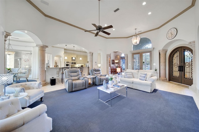 living room featuring french doors, a towering ceiling, ceiling fan, and decorative columns