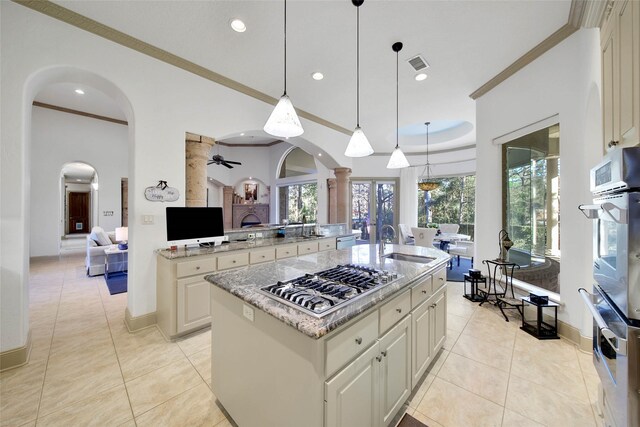 kitchen featuring stainless steel appliances, an island with sink, hanging light fixtures, and crown molding