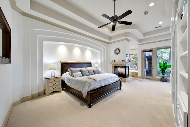 carpeted bedroom featuring ceiling fan, a multi sided fireplace, and a towering ceiling