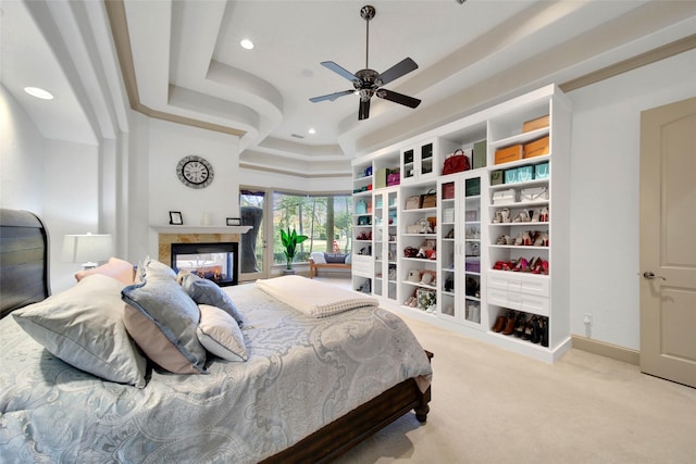 carpeted bedroom featuring a raised ceiling, a multi sided fireplace, and ceiling fan