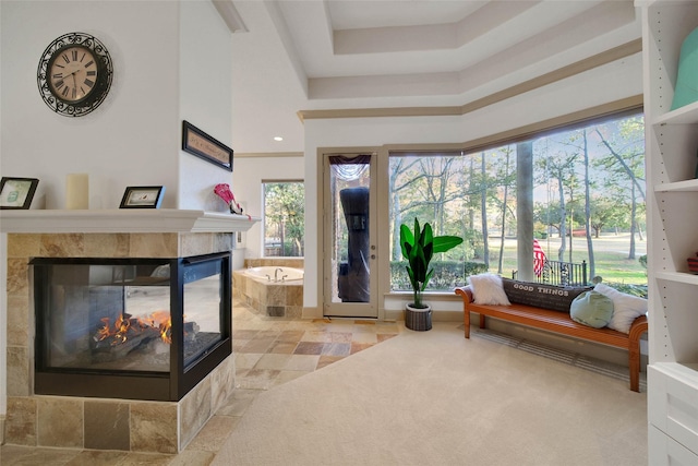 interior space featuring a tiled fireplace, a raised ceiling, and a healthy amount of sunlight